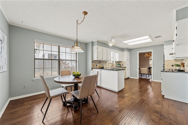 dining room with a skylight, baseboards, dark wood finished floors, and a ceiling fan