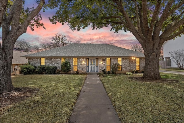 view of front of property featuring roof with shingles and a lawn