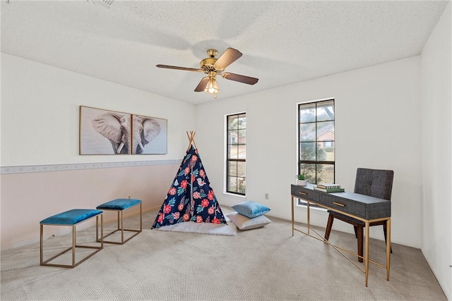 playroom featuring carpet floors, ceiling fan, and a textured ceiling