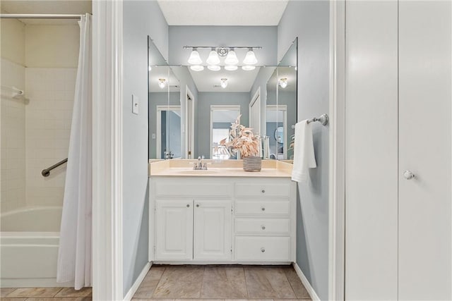 bathroom with baseboards, shower / bath combo with shower curtain, vanity, and tile patterned floors