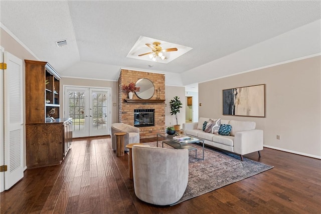 living room featuring french doors, dark wood-style flooring, a brick fireplace, and visible vents