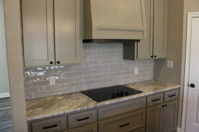 kitchen with decorative backsplash, black electric cooktop, and light stone countertops