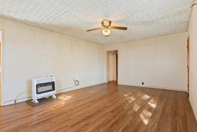 empty room featuring ceiling fan, wood-type flooring, and heating unit