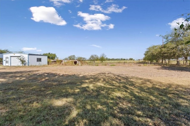 view of yard featuring an outbuilding, a rural view, and a garage