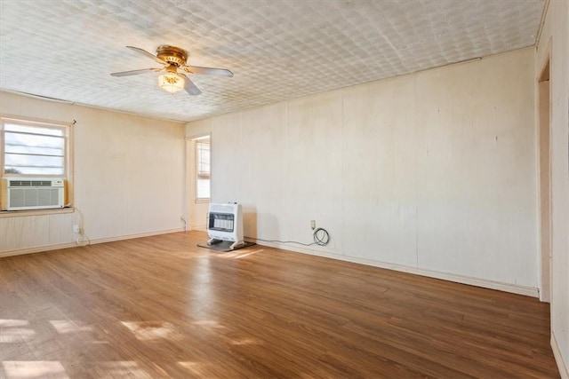 spare room with wood-type flooring, heating unit, and a wealth of natural light