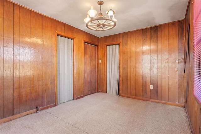 empty room with a chandelier and wooden walls