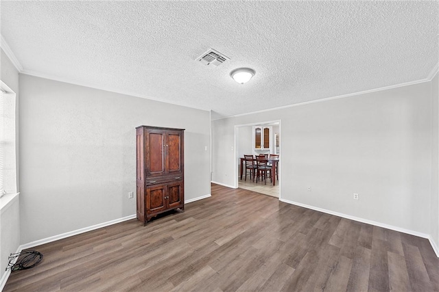 empty room featuring hardwood / wood-style floors, ornamental molding, and a textured ceiling