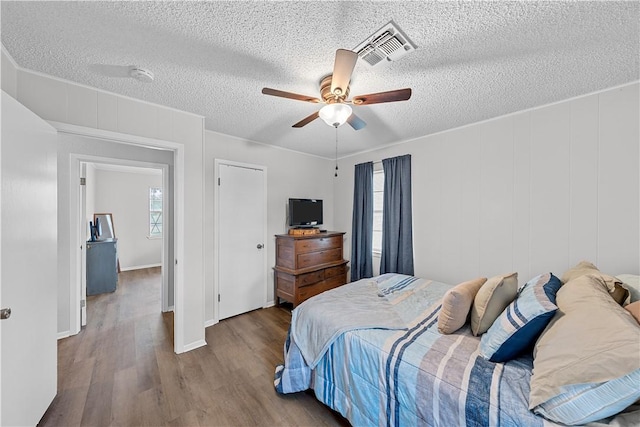 bedroom with hardwood / wood-style flooring, ceiling fan, a textured ceiling, and multiple windows