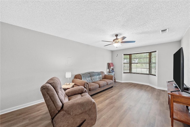 living room with ceiling fan, a textured ceiling, and hardwood / wood-style flooring