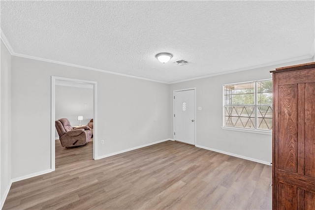 spare room featuring a textured ceiling, light hardwood / wood-style flooring, and ornamental molding