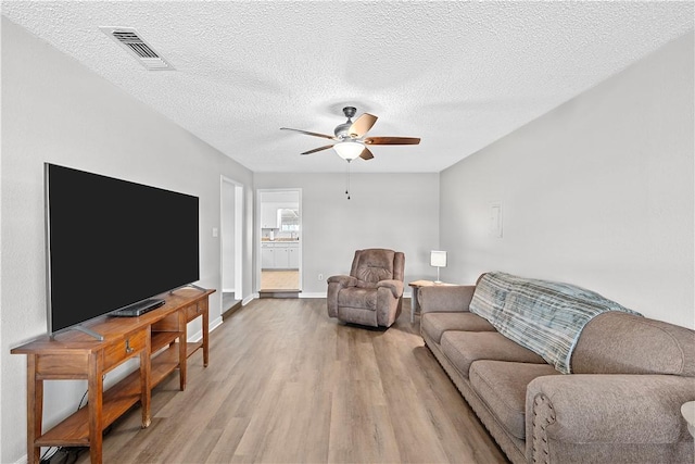 living room with hardwood / wood-style floors, a textured ceiling, and ceiling fan