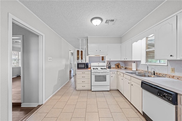 kitchen with white appliances, a textured ceiling, sink, light tile patterned floors, and white cabinetry