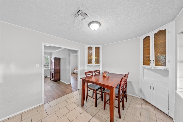 dining room with a textured ceiling and light hardwood / wood-style flooring