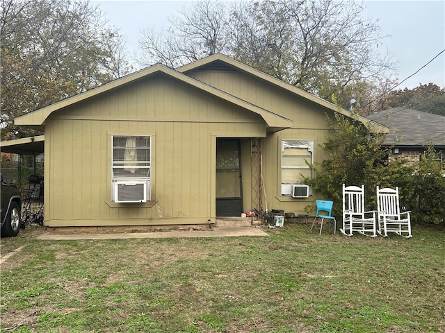 rear view of property featuring a yard, cooling unit, and a carport