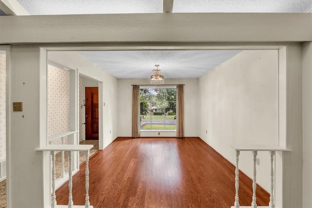 interior space featuring a textured ceiling, a notable chandelier, and hardwood / wood-style flooring