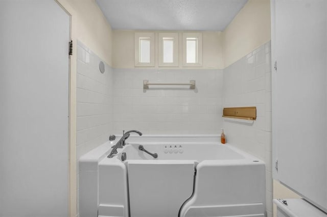 bathroom with a textured ceiling and a tub to relax in