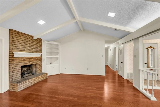 unfurnished living room featuring a textured ceiling, lofted ceiling with beams, hardwood / wood-style flooring, and a brick fireplace