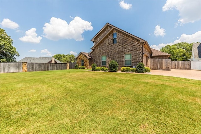 view of front of property with brick siding, concrete driveway, a fenced backyard, an attached garage, and a front yard