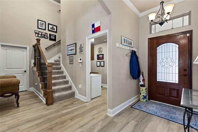 foyer entrance featuring arched walkways, light wood-style flooring, baseboards, stairway, and crown molding