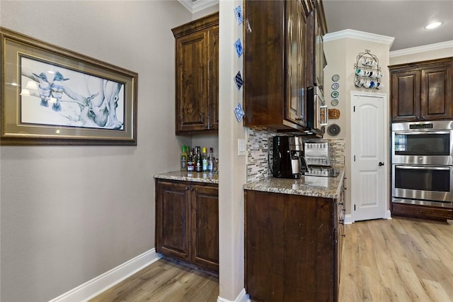 kitchen with ornamental molding, double oven, light stone counters, and backsplash