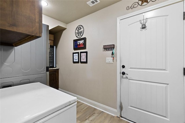 washroom with light wood-style flooring, visible vents, and baseboards