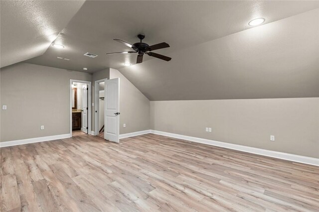 bonus room featuring baseboards, visible vents, a ceiling fan, vaulted ceiling, and light wood-style floors