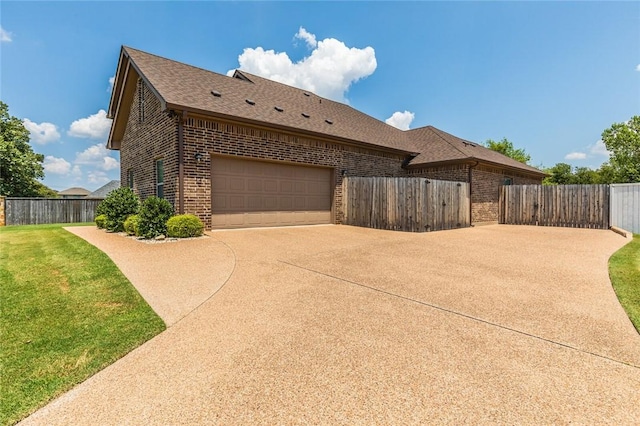 view of side of property featuring brick siding, roof with shingles, concrete driveway, a garage, and a fenced backyard