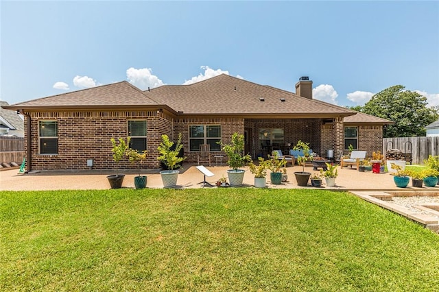 rear view of house featuring brick siding, a yard, fence, and a patio