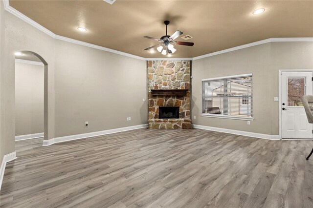 living area featuring visible vents, arched walkways, a ceiling fan, crown molding, and light wood-type flooring