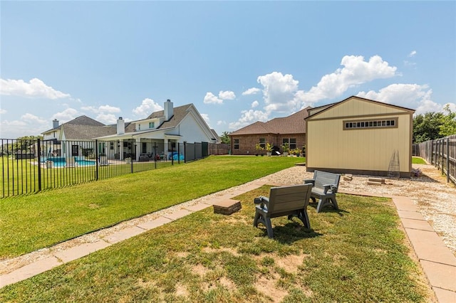 view of yard featuring a storage shed, a fenced backyard, a fenced in pool, and an outbuilding