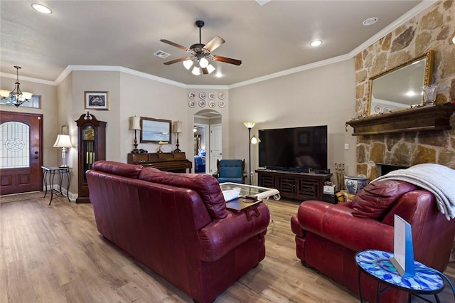 living room featuring arched walkways, visible vents, light wood-style flooring, ornamental molding, and ceiling fan with notable chandelier