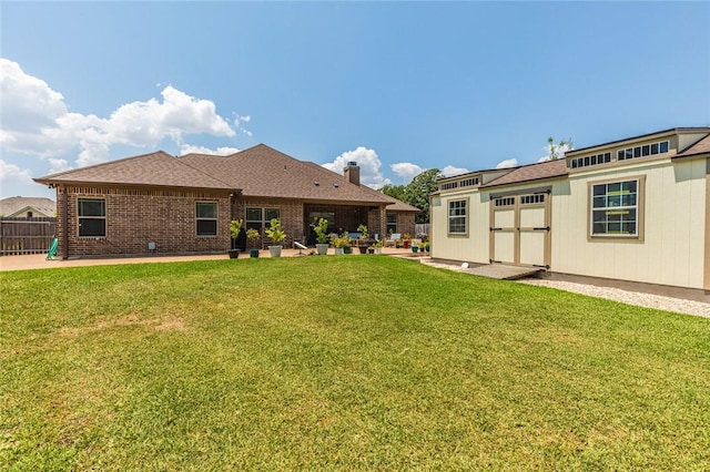 back of property with brick siding, fence, a lawn, and a patio