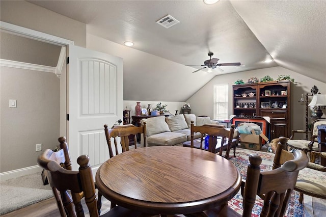 dining space with baseboards, visible vents, a ceiling fan, vaulted ceiling, and a textured ceiling