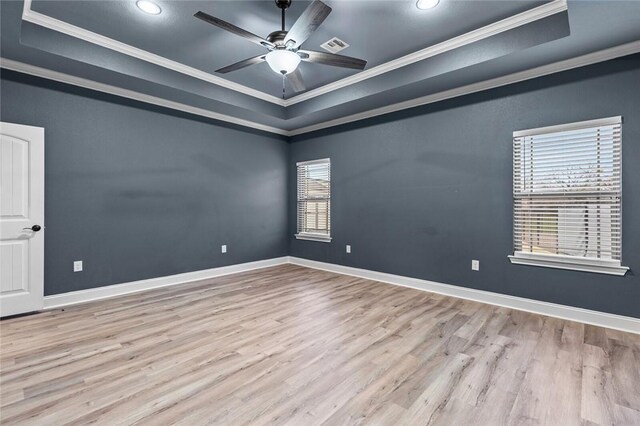 bedroom with visible vents, a raised ceiling, wood finished floors, ensuite bathroom, and crown molding