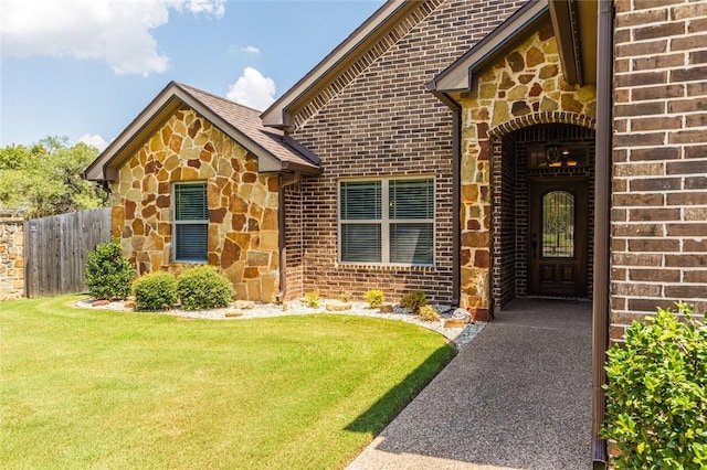 property entrance featuring a yard, stone siding, and brick siding