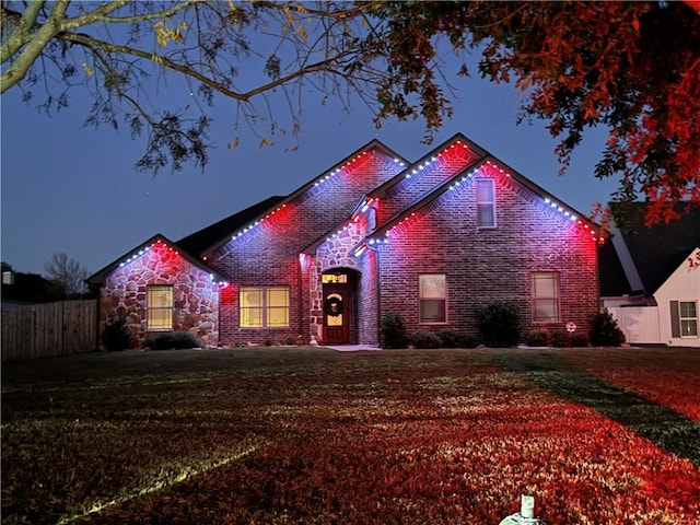 view of front of house with fence, a front lawn, and brick siding