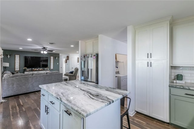 kitchen featuring white cabinetry, decorative backsplash, stainless steel fridge, and dark wood-type flooring