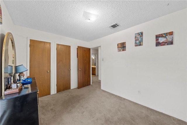 carpeted bedroom with a textured ceiling and multiple closets