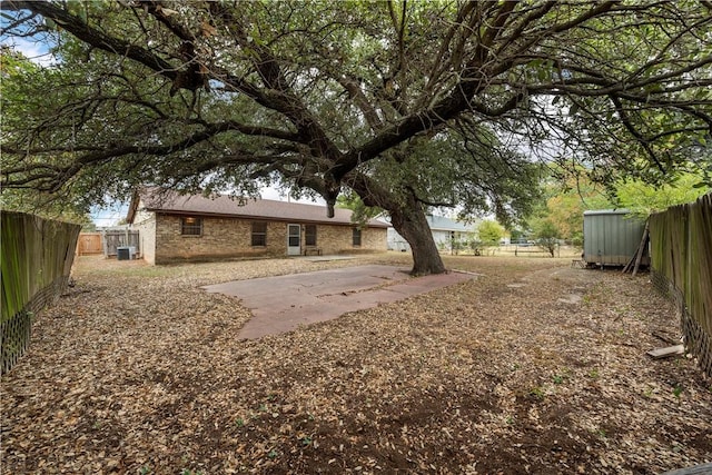 view of yard with a patio, central AC unit, and a storage shed