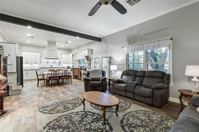 living room featuring ceiling fan, crown molding, and light hardwood / wood-style flooring