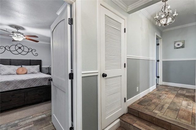 bedroom with a textured ceiling, ornamental molding, and ceiling fan with notable chandelier