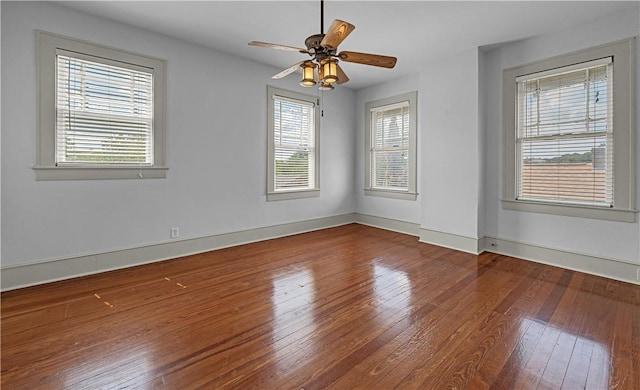 empty room with a wealth of natural light, ceiling fan, and hardwood / wood-style flooring