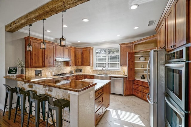 kitchen featuring kitchen peninsula, appliances with stainless steel finishes, a kitchen bar, decorative light fixtures, and light tile patterned flooring