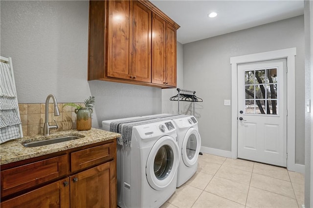 laundry room featuring cabinets, light tile patterned floors, sink, and washing machine and dryer