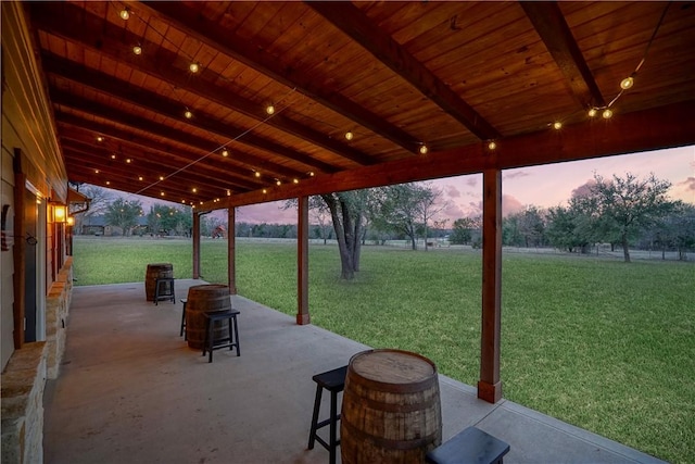 patio terrace at dusk featuring a yard