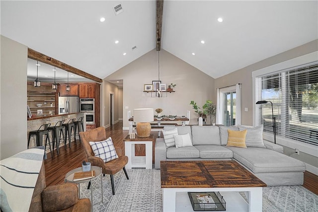 living room featuring a chandelier, beamed ceiling, light hardwood / wood-style floors, and high vaulted ceiling