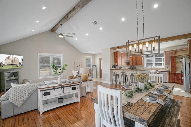 dining space with beamed ceiling, light hardwood / wood-style flooring, high vaulted ceiling, and ceiling fan with notable chandelier