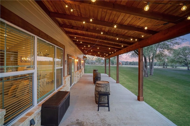 patio terrace at dusk featuring a lawn