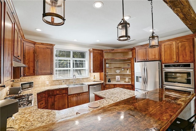 kitchen with light stone countertops, tasteful backsplash, stainless steel appliances, sink, and decorative light fixtures