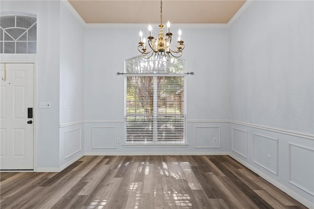 unfurnished dining area with crown molding, dark wood-type flooring, and a chandelier